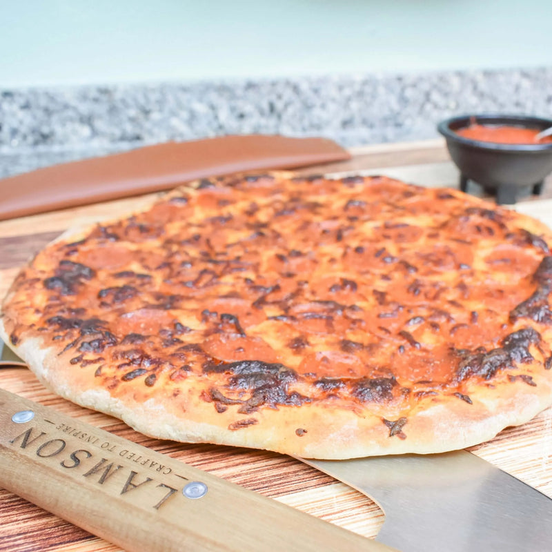 Lamson | 12 Pizza Rocker with Walnut Handles on a cutting board, showcasing its precision slicing tool for clean pizza cuts, ideal for Athens Cooks' curated kitchen collection.