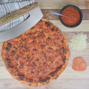 Lamson | 12 Pizza Rocker with Walnut Handles slicing a pizza next to a bowl of red sauce and shredded cheese, highlighting its precise cutting capability.