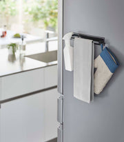 Yamazaki Home - Magnetic Kitchen Towel Hanger on fridge, holding a spray bottle, kitchen towel, and oven mitt, showcasing its organizing capability in a modern kitchen setting.