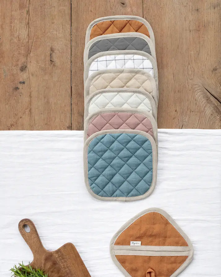 MagicLinen linen pot-holder in charcoal gray, featuring quilted detailing and a convenient hanging loop, displayed alongside kitchen accessories on a wooden surface.