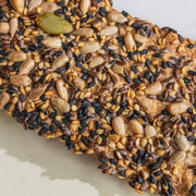 Potters Table - Seeded Olive Oil Flatbreads: Close-up of seed-topped crispbread featuring sesame, flax, sunflower, and pumpkin seeds, sprinkled with salt on a thin, crunchy base.