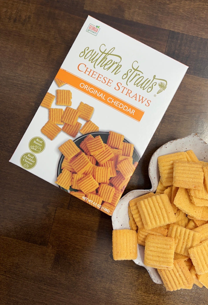 Southern Straws | Cheese Straws - Original Cheddar box beside a dish with crispy, square cheese wafers, showcasing a handcrafted, nostalgic Southern snack.