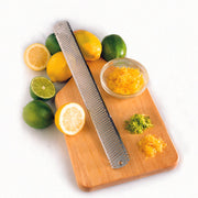 Microplane | Classic Series Stainless Steel Zester (No Handle) on a cutting board with citrus fruits and zest piles, exemplifying kitchen precision and versatility.