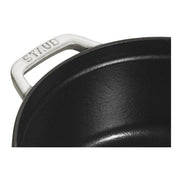 Staub | Round Cocottes - 5.5 qt White Truffle: Close-up of black enameled interior and white handle, branded STAUB, showcasing craftsmanship ideal for versatile cooking.