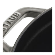 Close-up of Staub | Round Cocottes - 7 qt Graphite side handle with STAUB engraving, showcasing its durable craftsmanship and black enameled interior, ideal for versatile cooking.