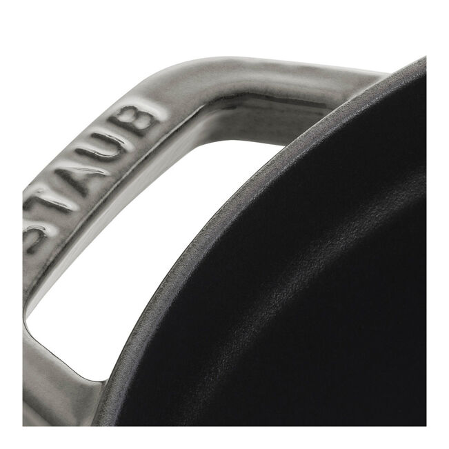 Close-up of Staub | Round Cocottes - 7 qt Graphite side handle with STAUB engraving, showcasing its durable craftsmanship and black enameled interior, ideal for versatile cooking.