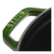 Staub | Round Cocottes - 5.5 qt Basil: Close-up of basil green handle with STAUB embossed, part of the cast iron pot with matte-black interior.