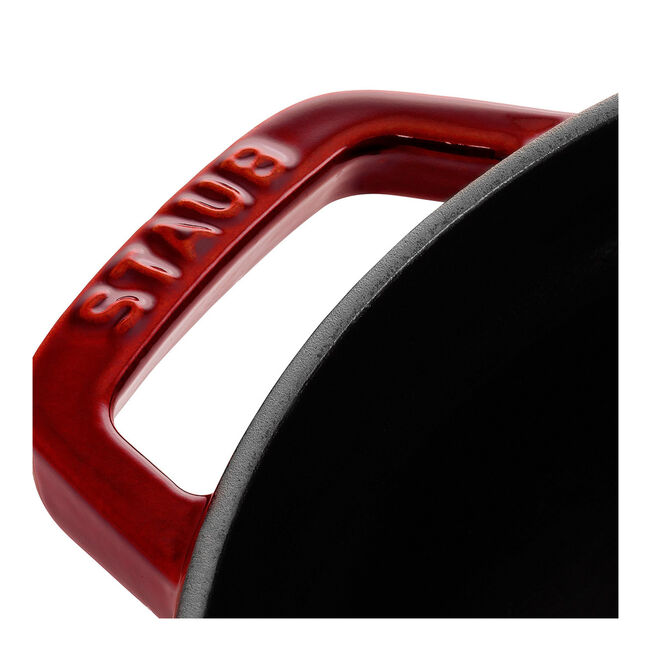 Close-up of the handle on a Staub | Round Cocottes - 5.5 qt Grenadine pot, showcasing the red enamel finish and STAUB branding.