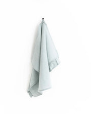 MagicLinen Ruffle Trim Tea Towel hanging on a hook, showcasing its soft texture and practical hanging loop, perfect for enhancing any kitchen's functionality and style.