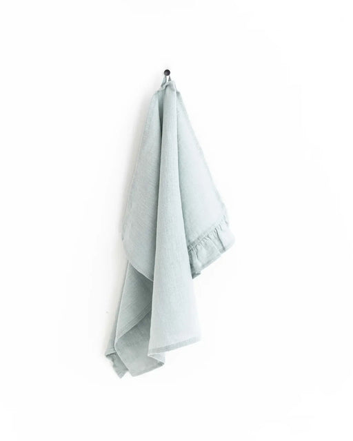 MagicLinen ruffle trim tea towel on a hook, highlighting its soft, absorbent linen texture and practicality for stylish kitchen use.