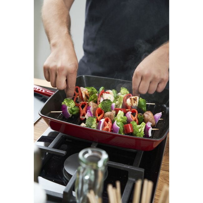 Staub Cast Iron Square Grill Pan - Grenadine shown, ideal for indoor grilling, featuring a ridged surface for authentic grill marks and exceptional heat retention.