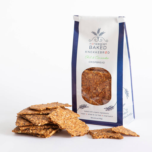 Norwegian Baked - Chili & Coriander Knekkebrød: Organic, vegan crispbread with seeds, in small-batch packaging. Displayed with textured crackers, enhancing meals with a zesty flavor.