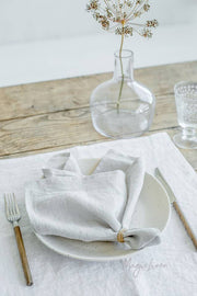 Set of 2 MagicLinen linen napkins on a table, accompanied by a napkin and fork, enhancing table decor with premium quality and timeless appeal.