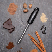 Microplane | Premium Classic Spice Rasp Grater on stone slab with nutmeg, cinnamon, chocolate, and other spices, ideal for grating tough foods like nutmeg and chocolate.