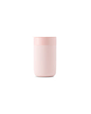 Reusable pink ceramic coffee mug with silicone sleeve and lid, designed for durability and style, ideal for eco-conscious coffee lovers.