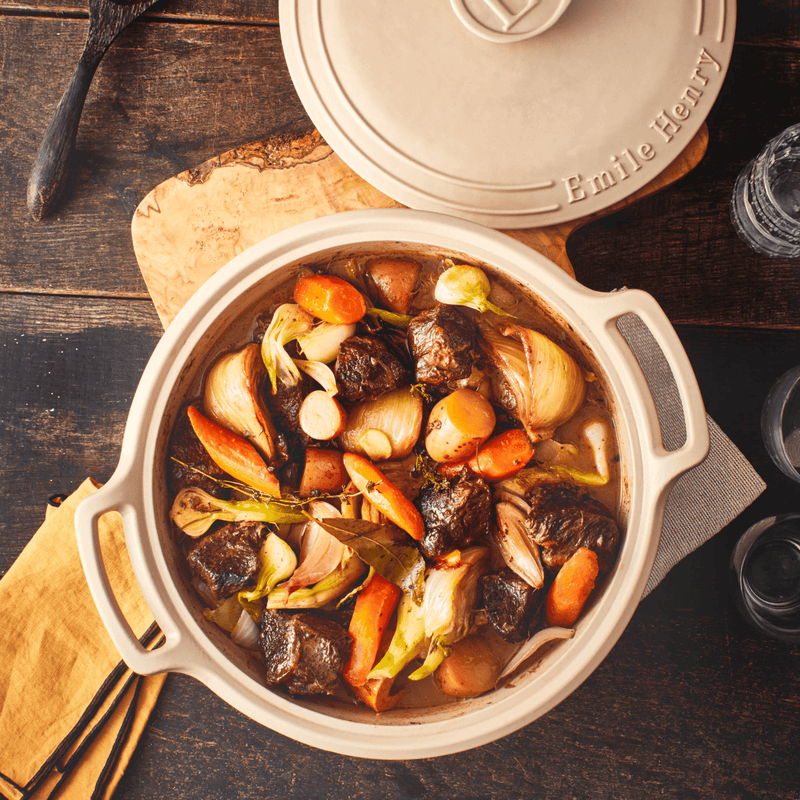 Emile Henry | Sublime 4 qt. Braiser, Crème, filled with braised beef, pearl onions, baby potatoes, carrots, and herbs, showcasing its versatility and culinary elegance.