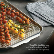 Hestan | OvenBond Tri-Ply Bakeware Half Sheet Pan with wire rack, showcasing roasted cherry tomatoes and rosemary, highlighting its durable, heat-resistant design.