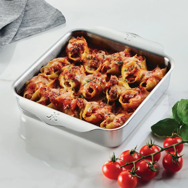 Hestan Provisions OvenBond Square Baker filled with cheese-topped conchiglioni, surrounded by cherry tomatoes and basil, showcasing its even heat distribution and durable design.