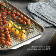 Hestan | Oven Bond Tri-Ply 5 Piece Set roasting pan with wire rack, displaying roasted cherry tomatoes. Oven and broiler safe to 600°F, ideal for even heat cooking.