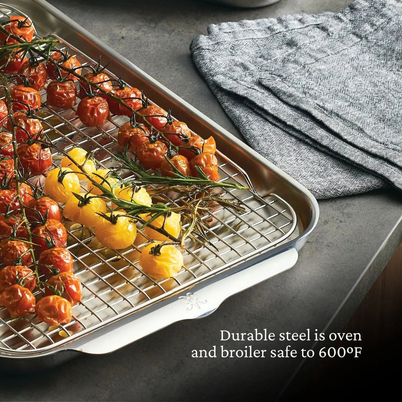 Hestan | Oven Bond Tri-Ply 5 Piece Set roasting pan with wire rack, displaying roasted cherry tomatoes. Oven and broiler safe to 600°F, ideal for even heat cooking.