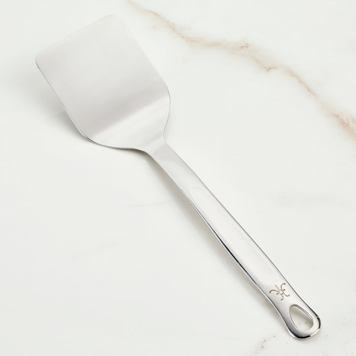 Hestan Stainless Steel Spatula/Turner on marble surface, ideal kitchen utensil from Athens Cooks for versatile cooking and precise flipping tasks.