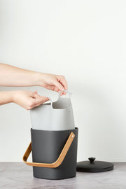 Hands holding Bamboozle - Composter Reusable Liner with grip loop, designed for easy compost transfer; durable silicone construction for practicality and style.