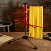 Marcato Tacapasta Pasta Drying Rack with red arms, holding freshly made pasta sheets on a wooden countertop. Includes removable rod for cutting and collecting pasta.