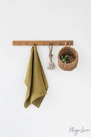 Linen tea towel hanging on a hook beside a basket with leaves, showcasing MagicLinen's durable and absorbent European flax kitchen towel.