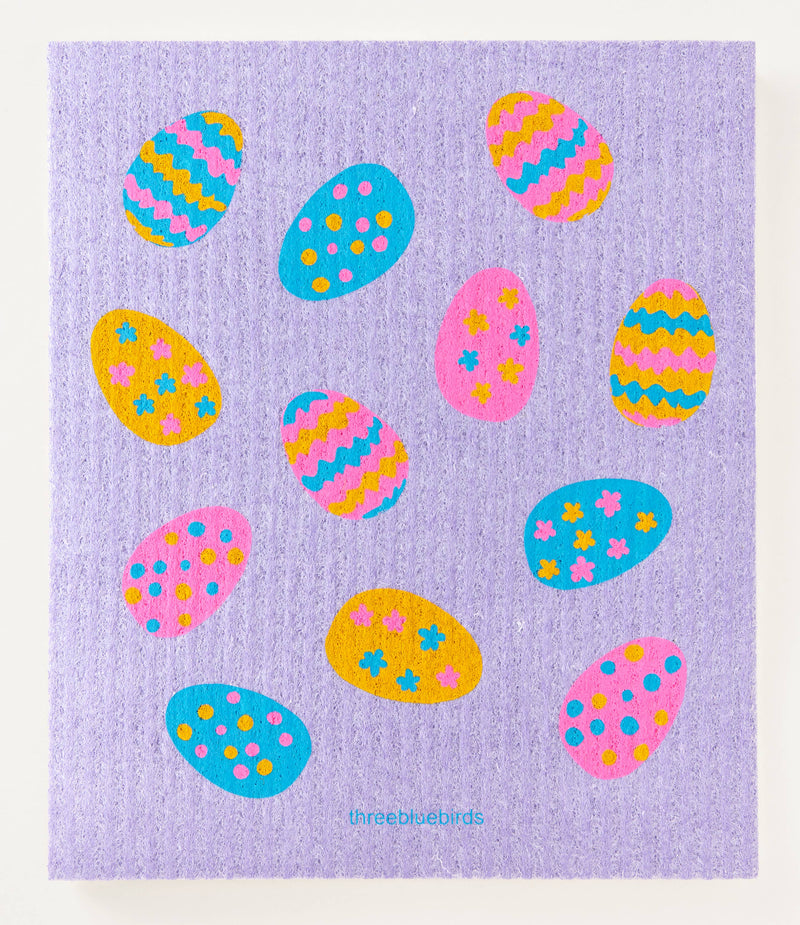 Three Bluebirds Swedish Dishcloths featuring colorful Easter eggs on a purple background, highlighting sustainable, biodegradable, and reusable features.