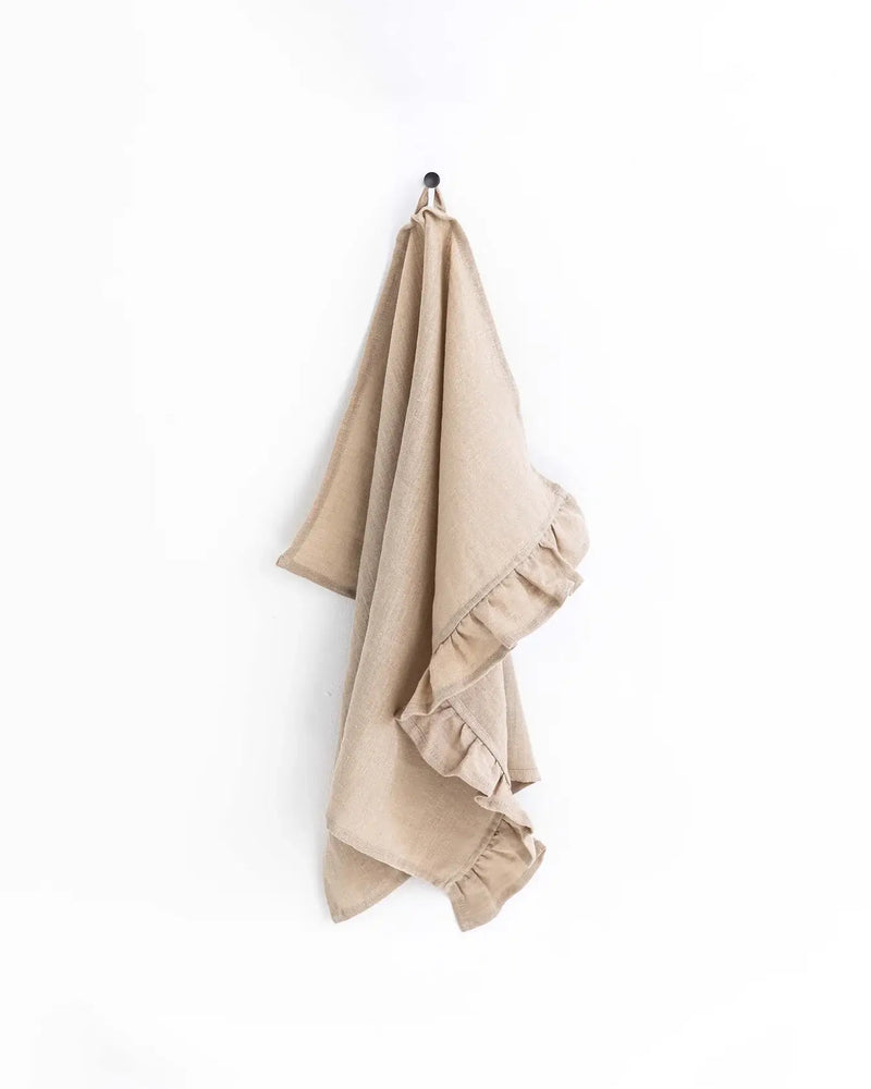MagicLinen - Ruffle trim tea towel hanging on a hook, showcasing its soft, absorbent linen material and practical hanging loop for kitchen use.