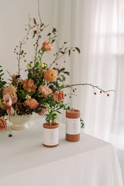 Mo&Co Home 100% Beeswax Pillar Candles in Terra Cotta displayed with flowers, ideal for home decor and celebrations.