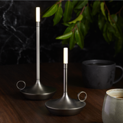 VANMOKUM | GRAYPANTS Wick Portable Rechargeable Lamp, a sleek, candle-flashlight hybrid in plated aluminum, ideal for intimate gatherings or restaurant patios.