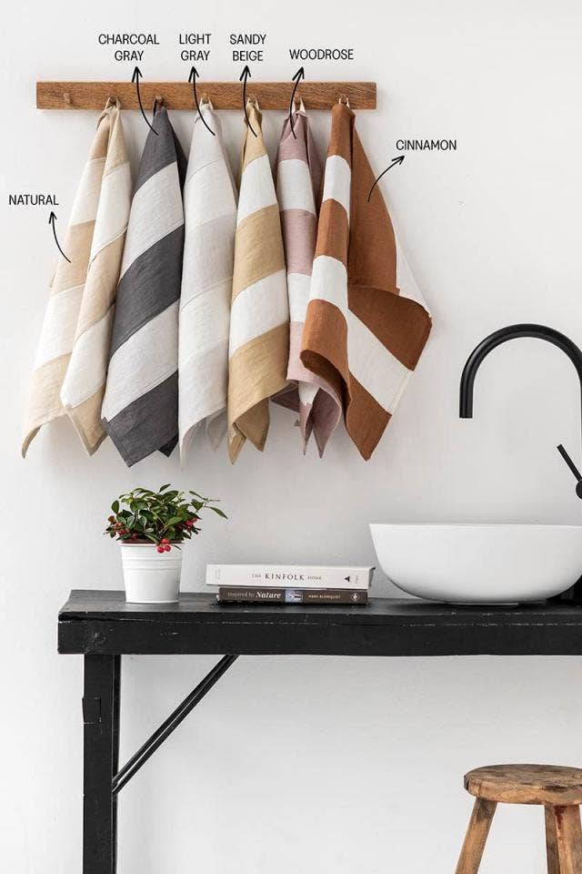 Striped linen tea towel with a hanging loop, showcased in a bathroom setting with a sink and towels, highlighting its design and zero-waste production.