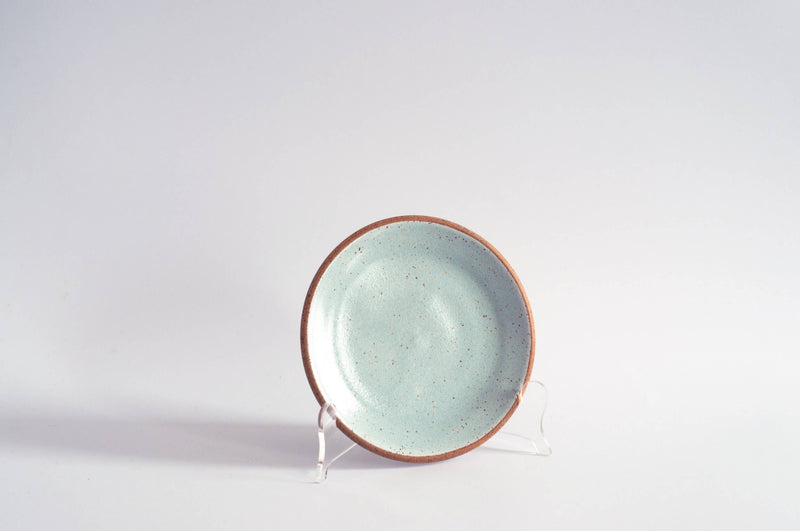 RachaelPots - Dessert Plate: Sage, a hand-thrown ceramic plate with speckled aqua glaze and reddish clay rim, displayed upright, perfect for desserts.