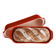 Emile Henry Loaf Bread Bakers: Red ceramic bread cloche with lid removed, showcasing a freshly baked artisan loaf inside, ideal for crusty, golden loaves.