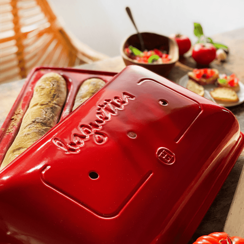 Emile Henry | Baguette Baker, Burgundy, with freshly baked baguettes under its lid, surrounded by bruschetta ingredients on a wooden table at Athens Cooks.