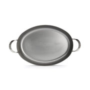 de Buyer | Oval Roasting Pan: A silver oval pan with two handles, ideal for roasting meats or vegetables, enhancing your cooking and dining experience.