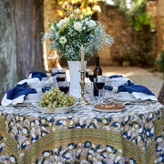 Dining table with Couleur Nature Forest Harvest tablecloth, set with wine, fruit, and flowers, reflecting Provençal charm in a garden setting.