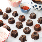 Nordic Ware | Bundt® Tea Cakes and Candies Pan with detailed mini Bundt shapes, perfect for creating elegant desserts like chocolate cakes, showcased alongside various baking ingredients.