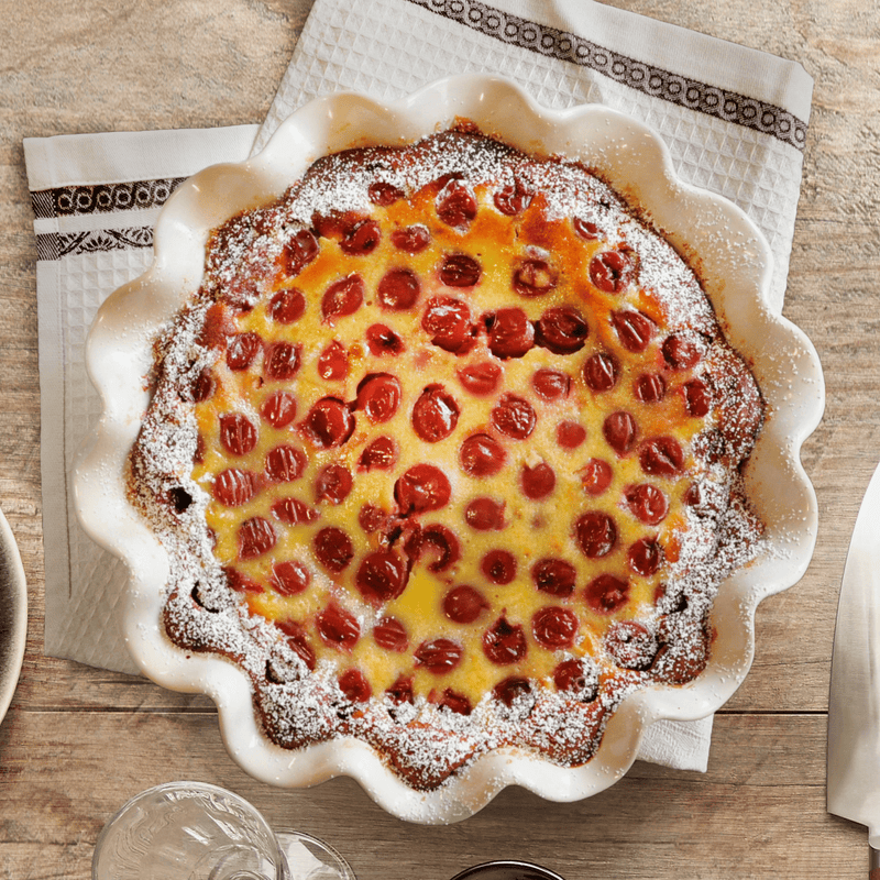 Emile Henry | Deep Ruffled Pie Dish, Clay, showcasing a baked cherry clafoutis, illustrating the dish's rustic elegance and functional scalloped edges.