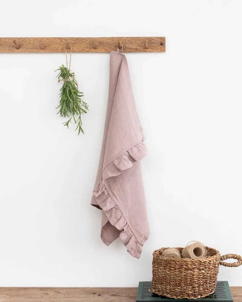 Ruffle trim tea towel hanging on a hook, showcasing its soft, absorbent linen texture and elegant design, perfect for any kitchen setting.