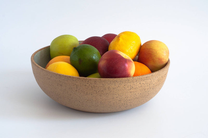 RachaelPots - Low Serving Bowl: Nude/Sage, hand-thrown speckled ceramic, filled with assorted fruit, showcasing its shallow design, ideal for kitchen or dining display.