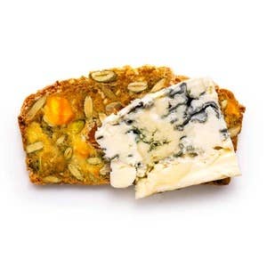 Rustic Bakery - Artisan Crisps, featuring a slice of multigrain bread with blue cheese, apricots, pistachios, and brandy, reflecting Athens Cooks' specialty food offerings.