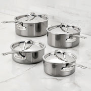 Hestan | Cookware, 1.5qt Saucepan + Lid: Four stainless-steel saucepans with lids, featuring ergonomic handles and Hestan nameplate, displayed on a marble countertop.