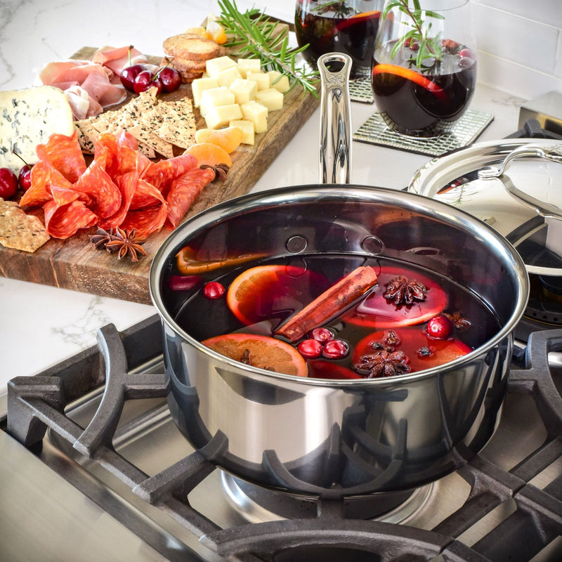 Hestan NanoBond 4qt Saucepan with mulled wine, featuring orange slices, cranberries, and spices on a stovetop, complemented by a charcuterie board and mulled wine glasses.