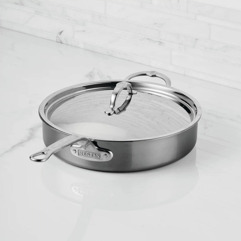 Hestan | Cookware, 3.5qt Sauté Pan + Lid on marble countertop, featuring a resilient titanium cooking surface and ergonomic handle, perfect for versatile kitchen use.