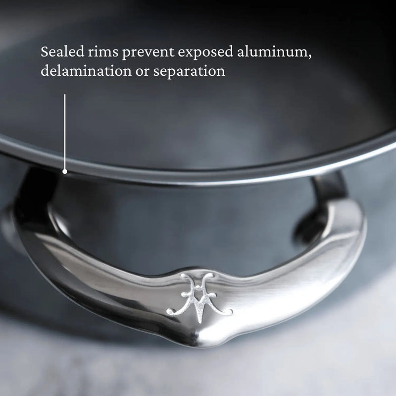 Close-up of Hestan | Cookware, 3.5qt Sauté Pan + Lid handle with monogram. Text highlights sealed rims preventing delamination, showcasing advanced NanoBond technology for durability.