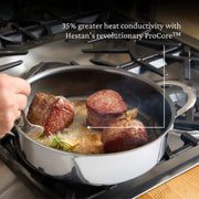 Hestan | Cookware, 3.5qt Sauté Pan + Lid searing beef medallions on a gas cooktop, showcasing ProCore™ heat conductivity with rosemary and garlic.