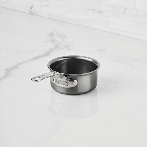 Hestan | Cookware, .75qt Butter Warmer Pan on a marble countertop, featuring a riveted handle stamped with “HESTAN,” ideal for melting and heating small portions.