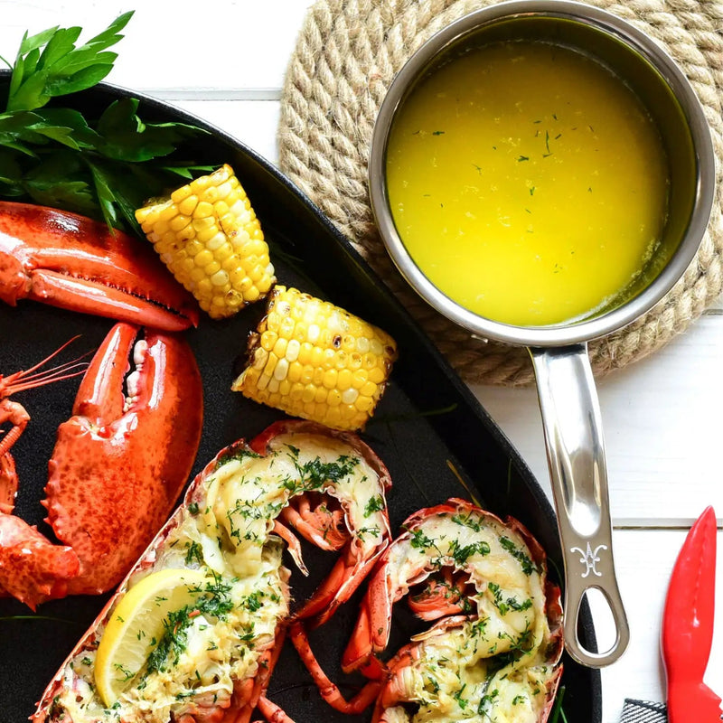 Seafood platter with lobster and grilled corn, highlighting the Hestan | Cookware .75qt Butter Warmer Pan, ideal for melting butter, featured in Athens Cooks' curated kitchen collection.